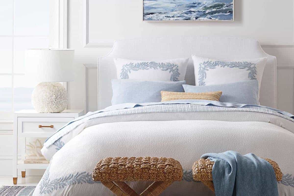 A white guest room with blue and white guest bedding on the bed.