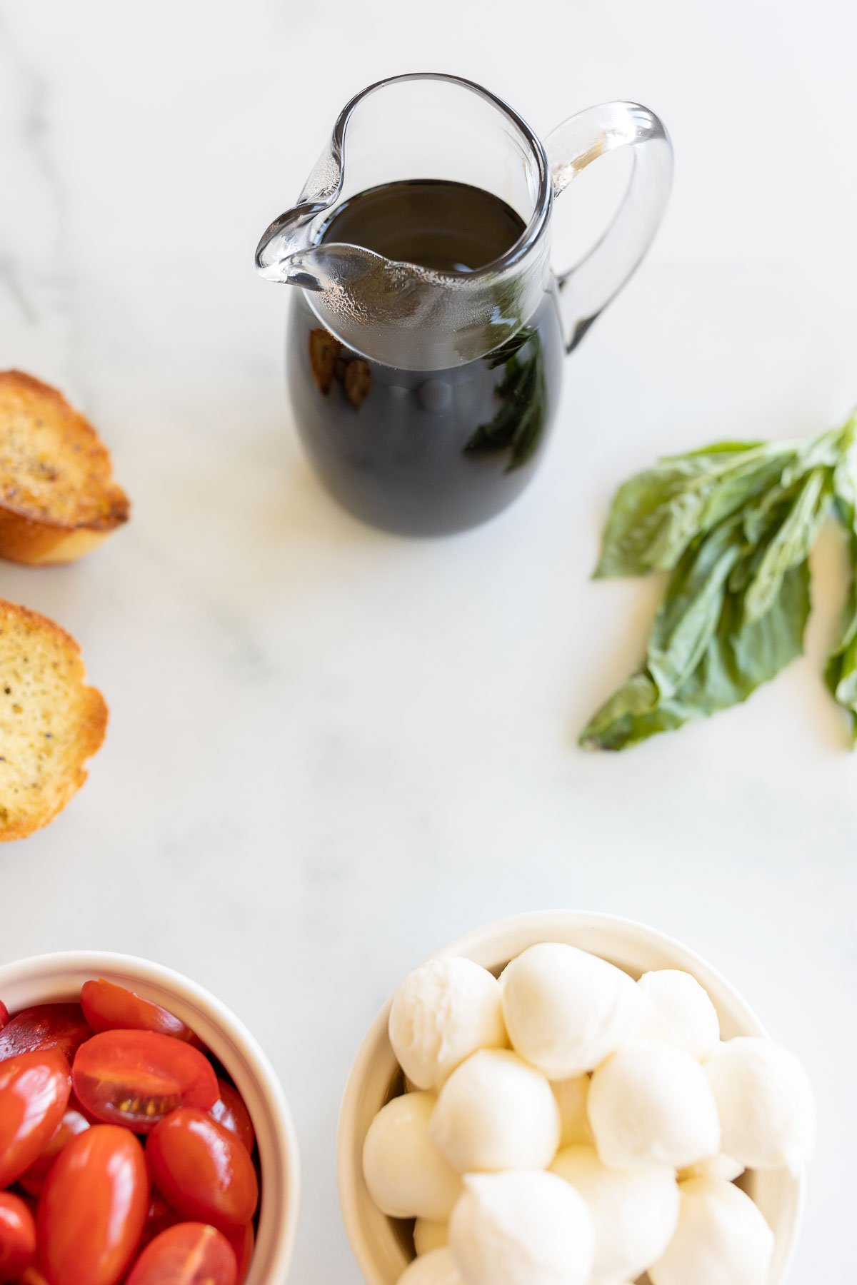 A bottle of balsamic reduction with ingredients for bruschetta.