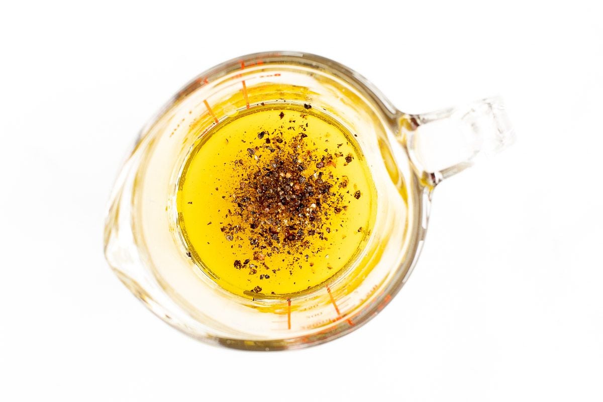 Oil and spices in a glass measuring cup.