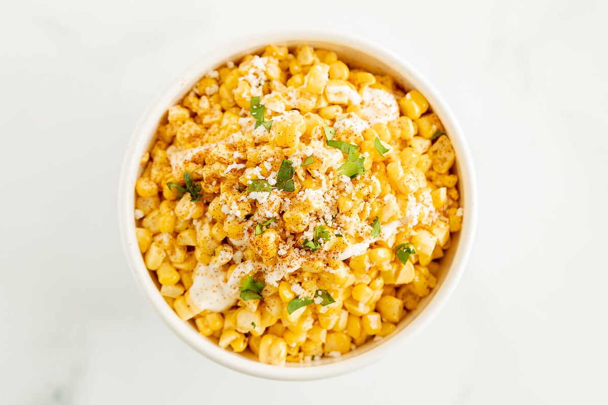 A white bowl of esquites (Mexican street corn salad).