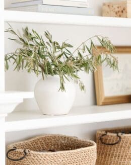 Bookshelf decor ideas of baskets, white pottery and artwork on white built ins.