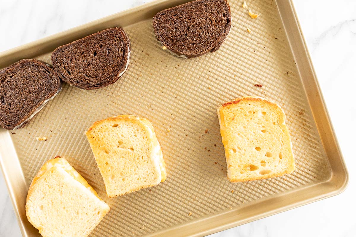 Oven grilled cheese sandwiches on a gold baking sheet.