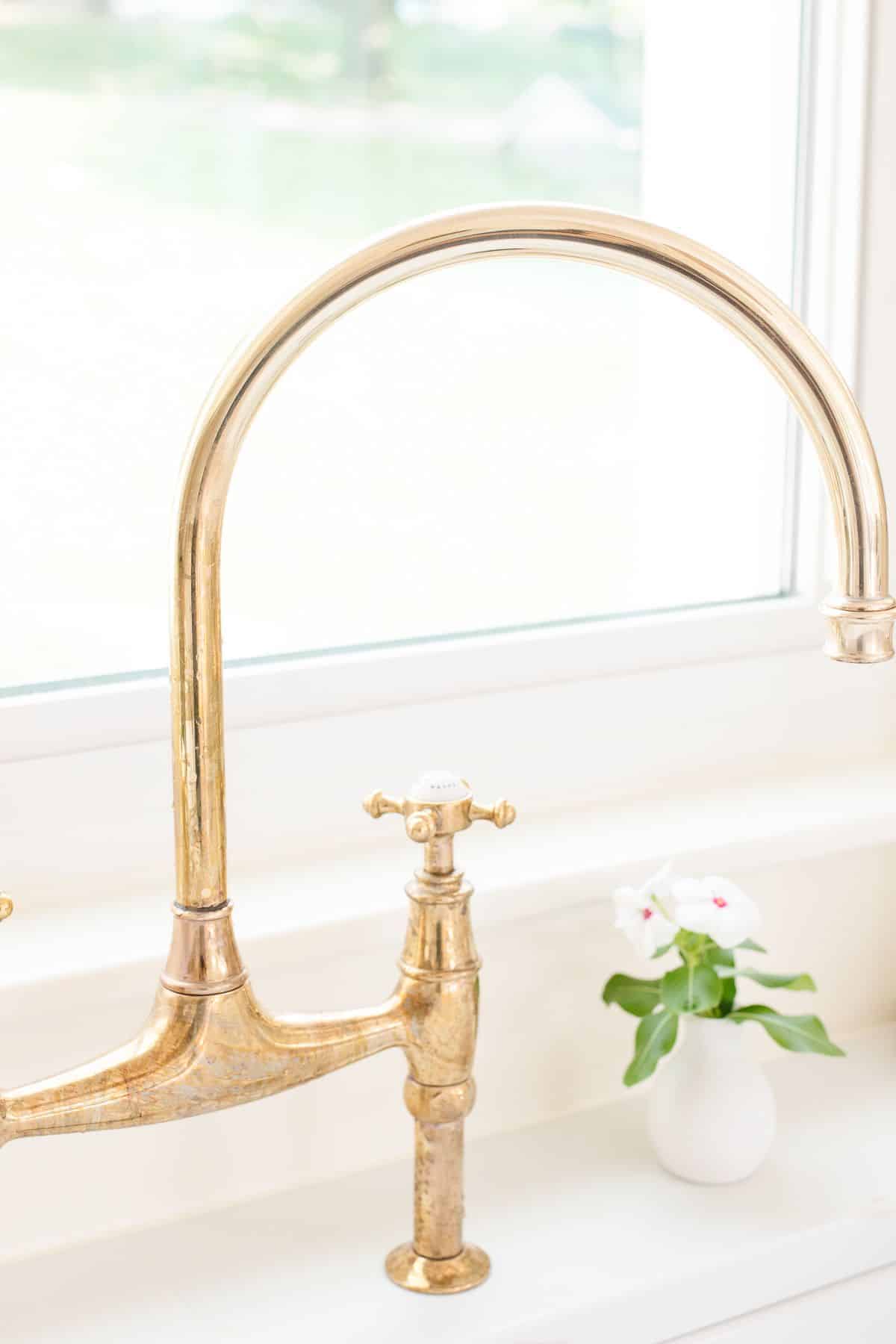 A brass kitchen faucet with some tarnish.