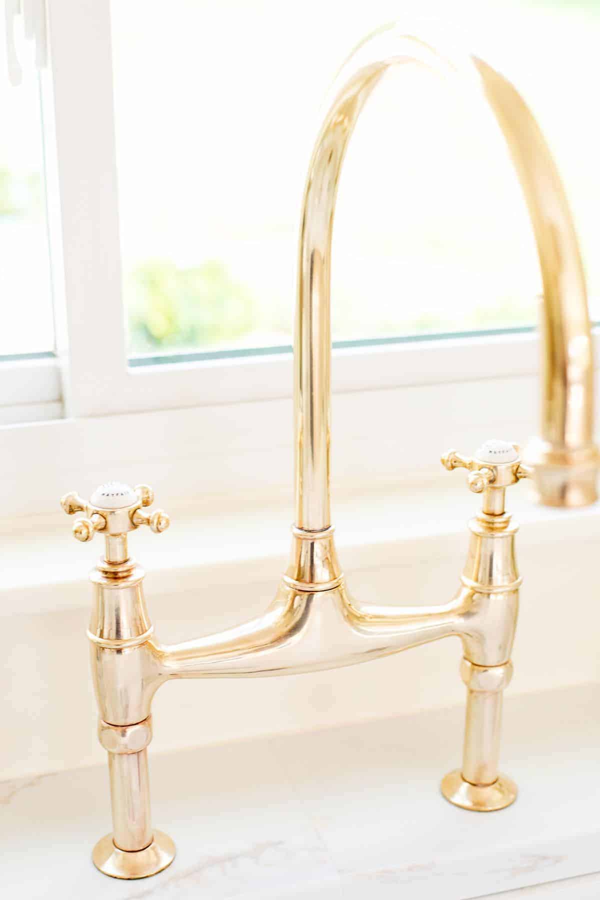 A brass bridge faucet that is shiny from brass polish.