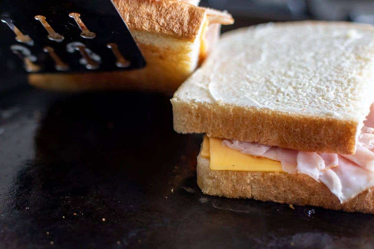 Two grilled ham and cheese sandwiches on a black cast iron pan.