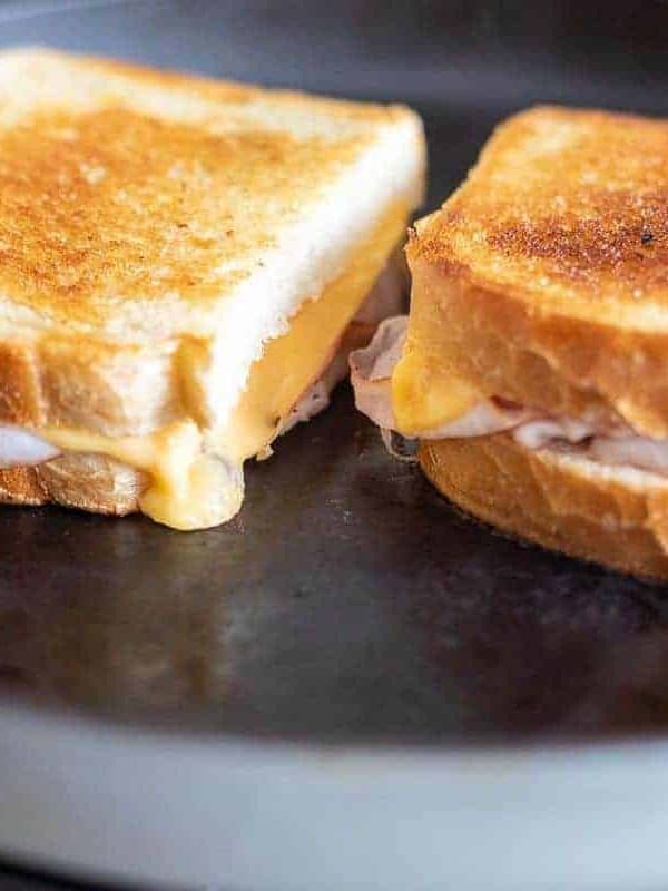 Two grilled ham and cheese sandwiches on a black cast iron pan.