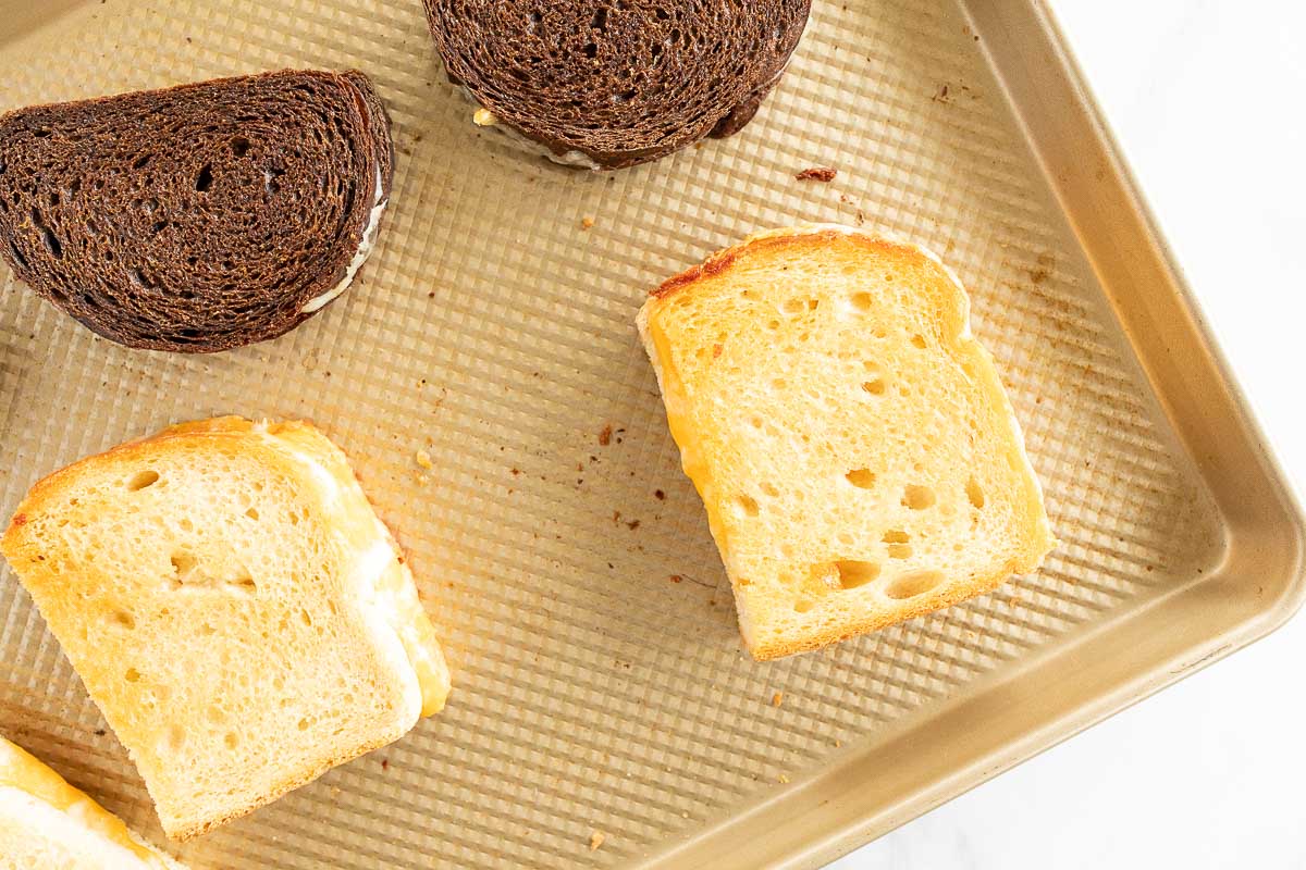 Oven grilled cheese sandwiches on a gold baking sheet.