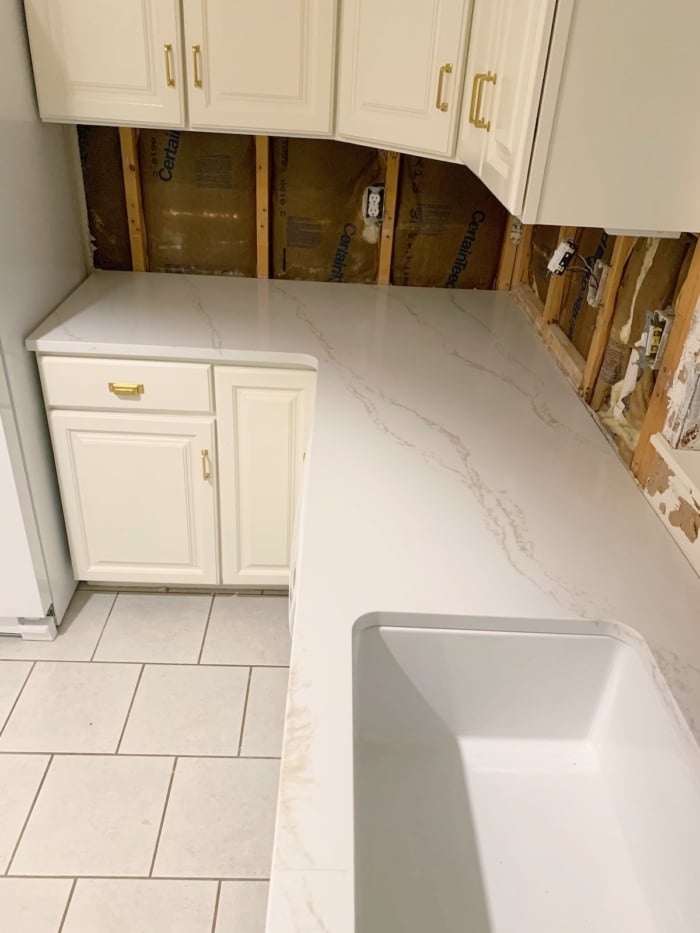 Quartz countertops being installed in a white kitchen.