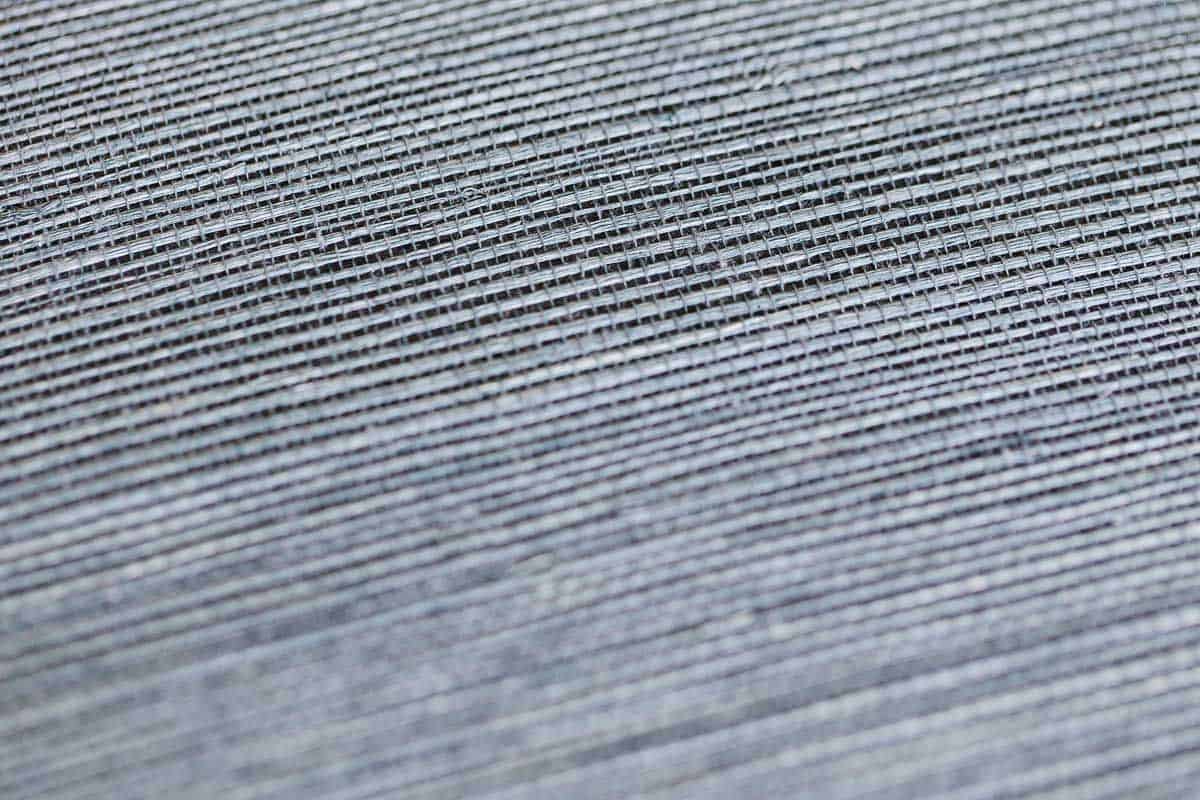 A close up of a navy blue grasscloth wallpaper