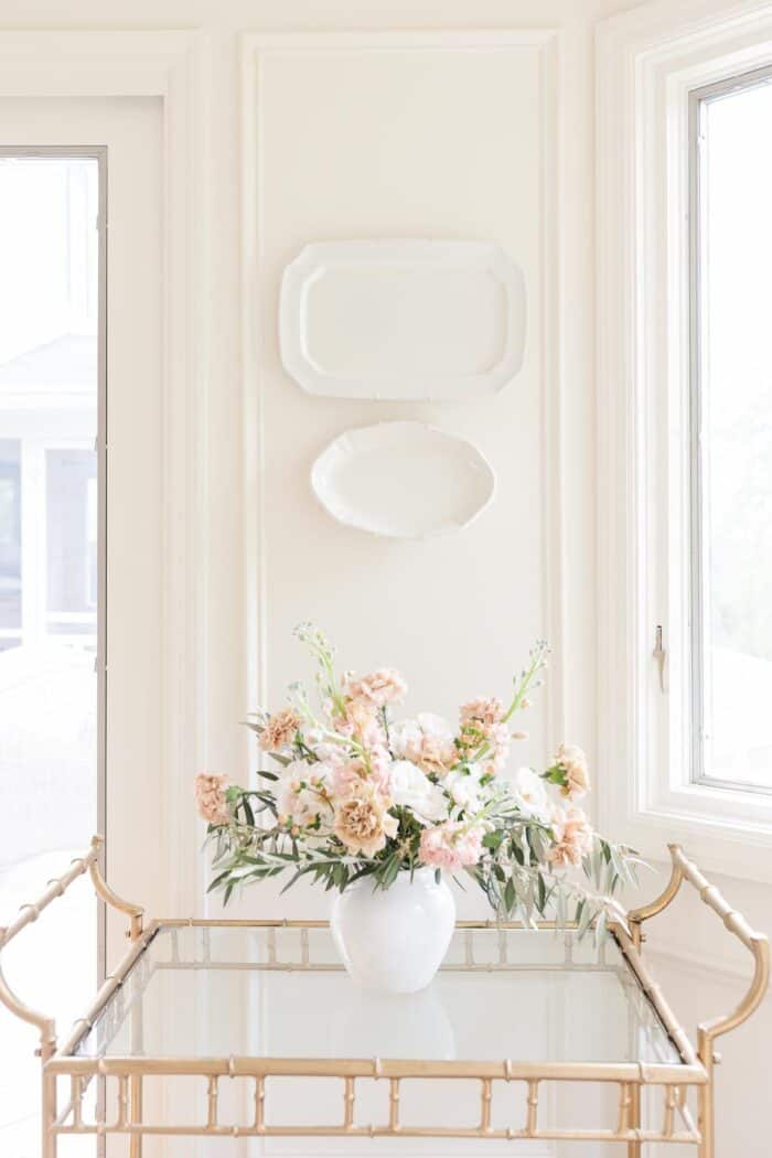 Antique Pink carnation arrangement on a brass bar cart in a cream room.