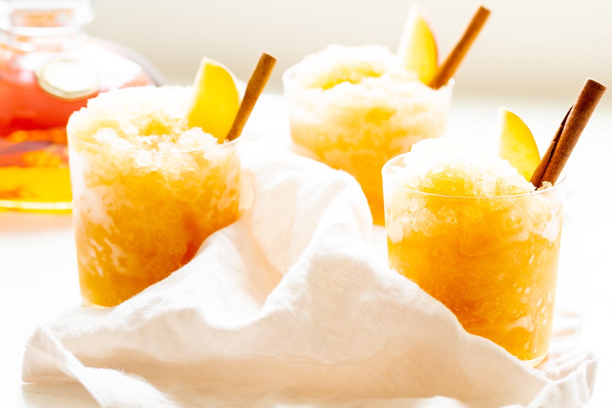 Apple cider slushies with bourbon, garnished with a cinnamon stick