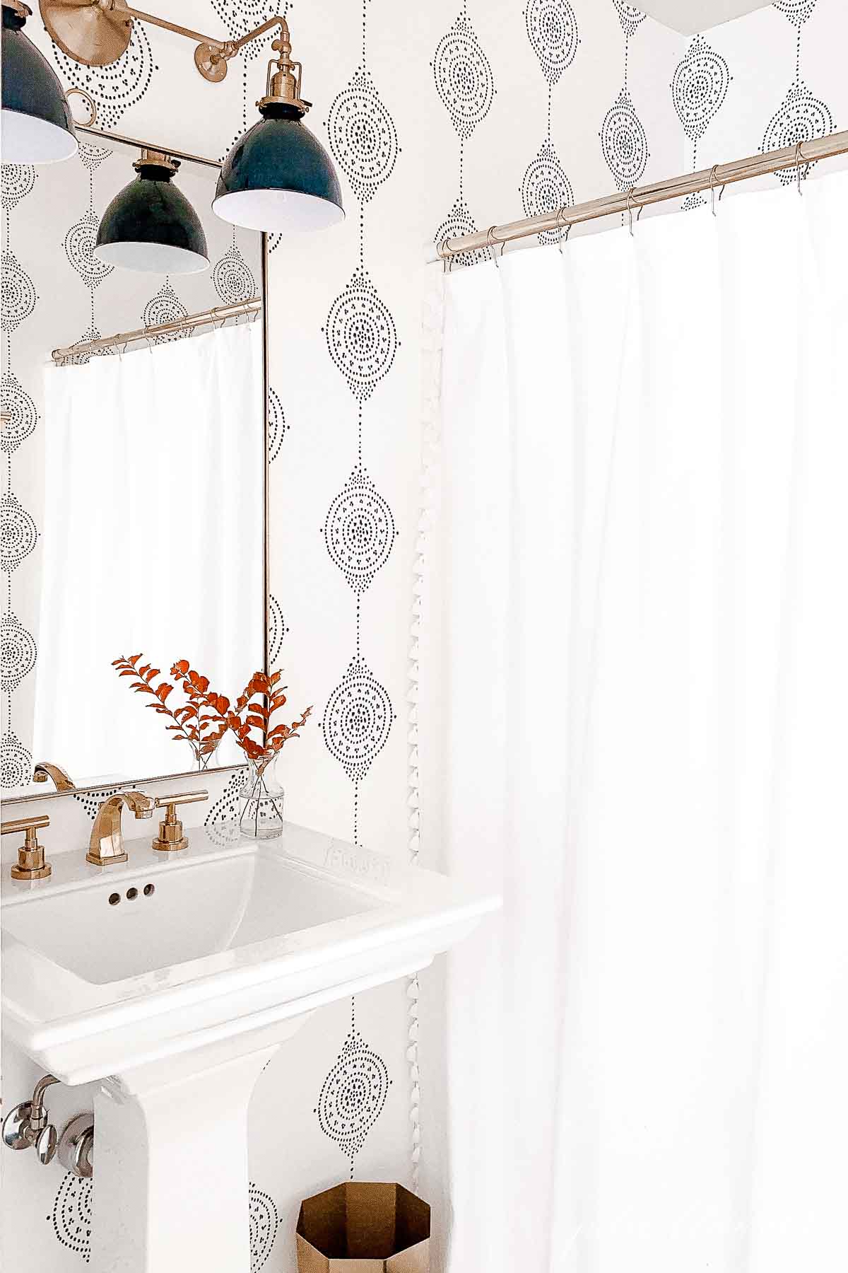 A bathroom with minimalist fall decor and a sink, mirror, and wallpaper.