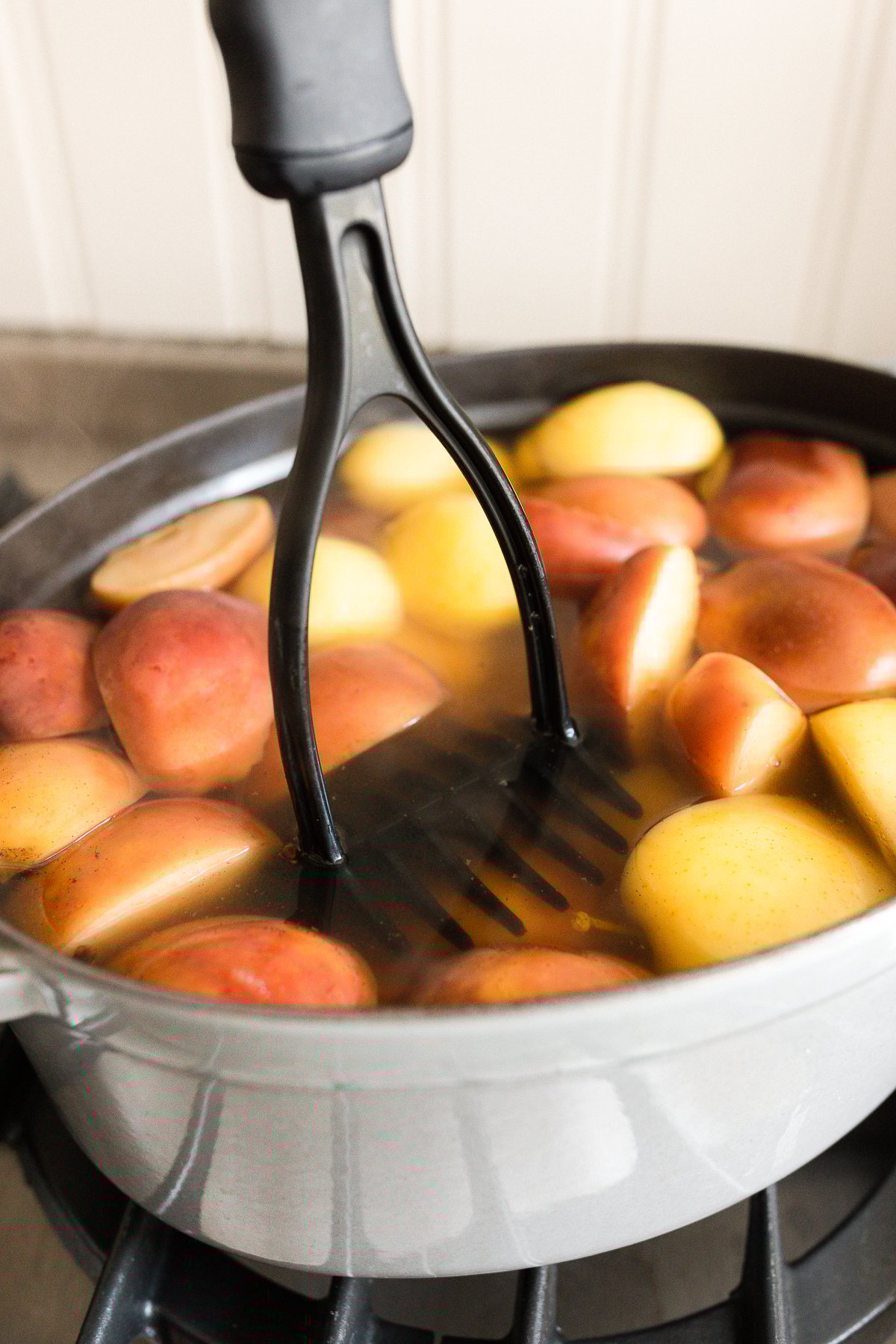 A potato masher smashing pears in