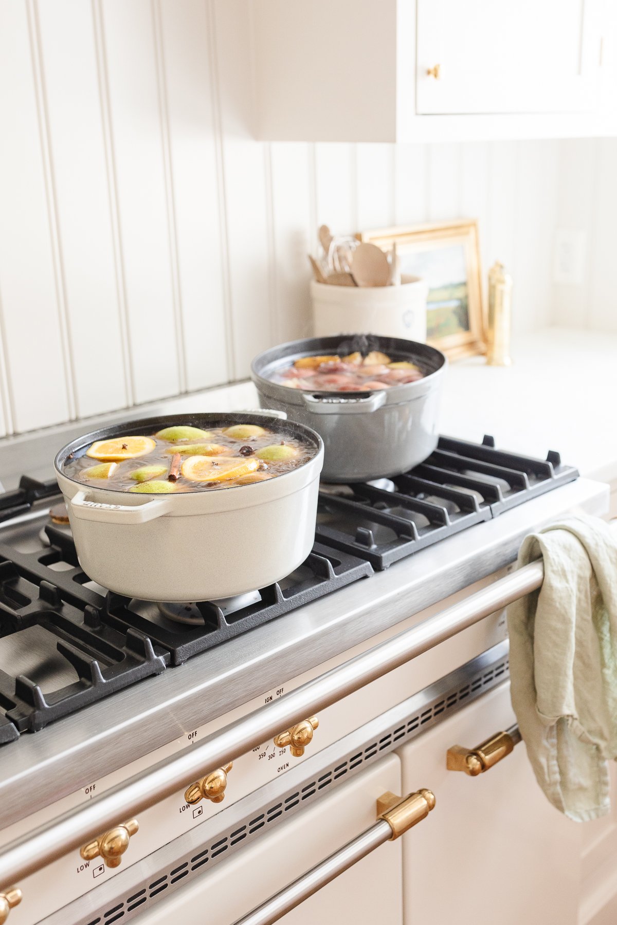 A white kitchen with a pot of pear cider on the stove.
