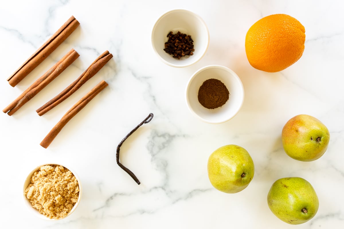Ingredients for pear cider on a white marble countertop.
