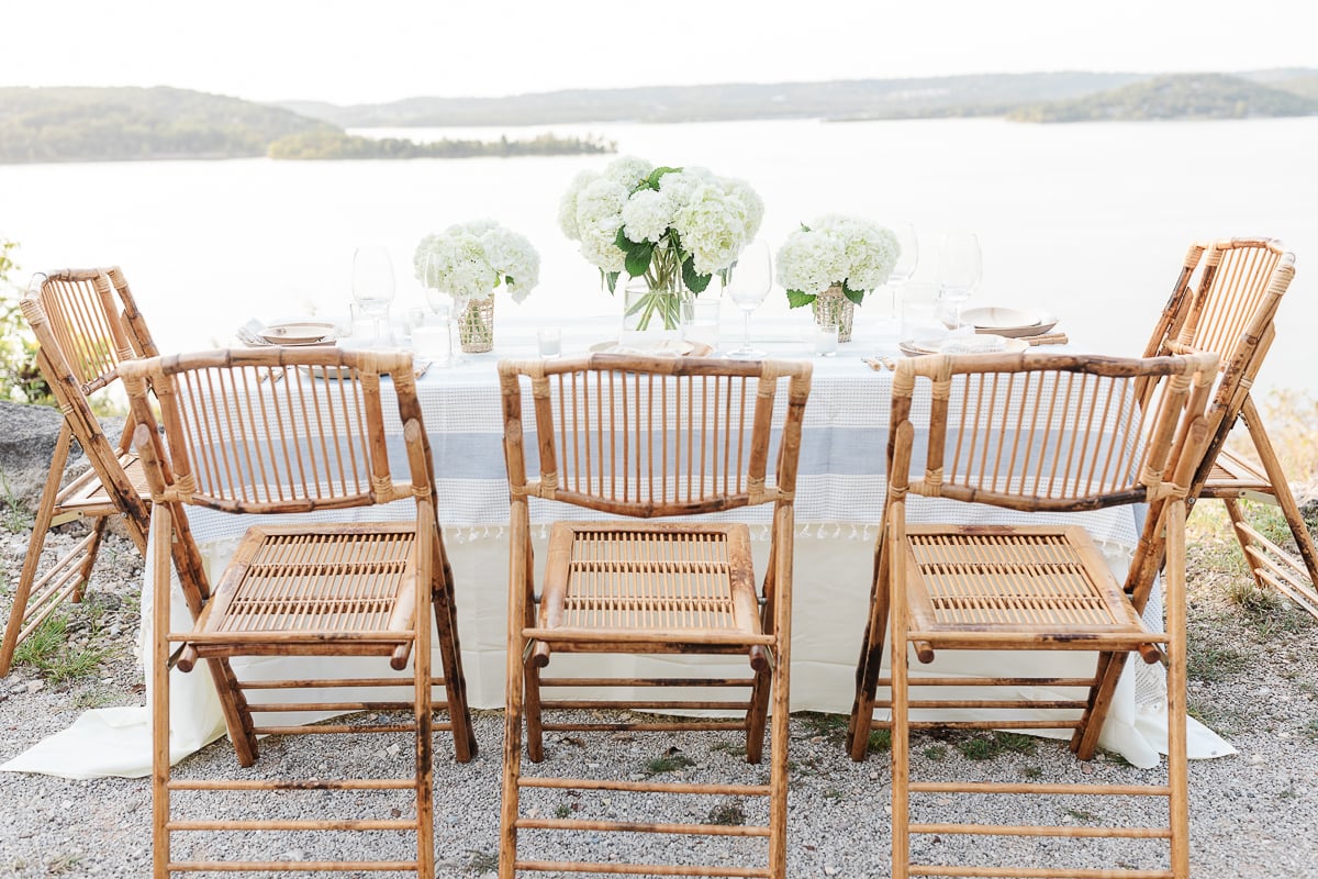 A table set up with bamboo dining chairs and water views for al fresco dining.