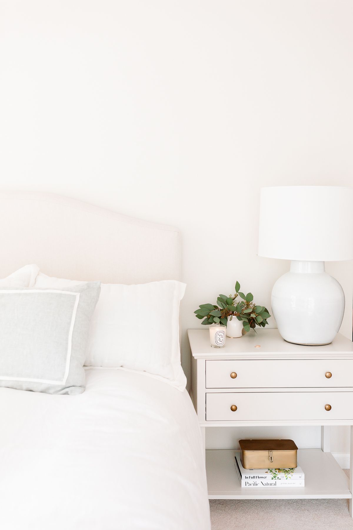 A cream bedroom with cream bed and greige nightstand