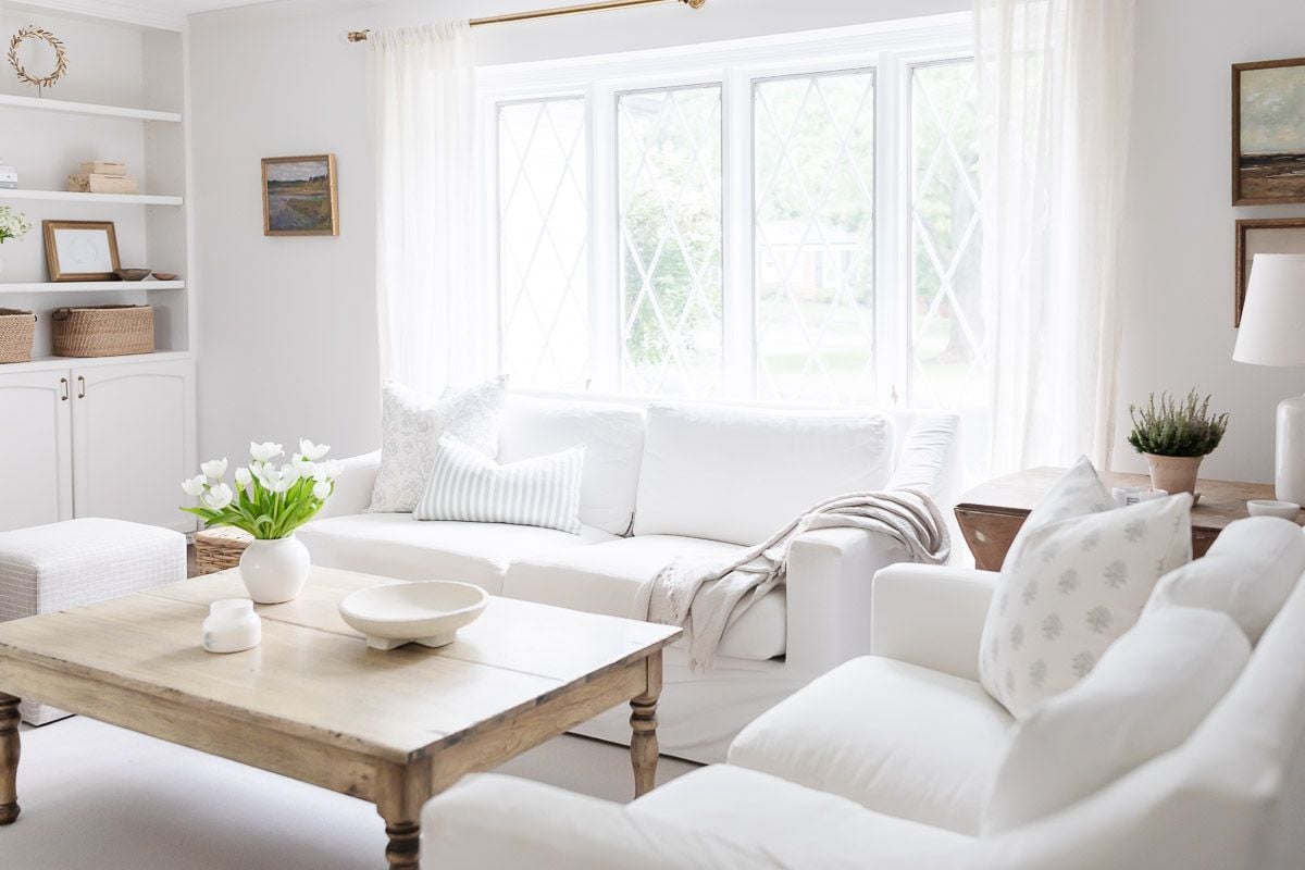 A white living room with built in bookshelves around a brick fireplace.