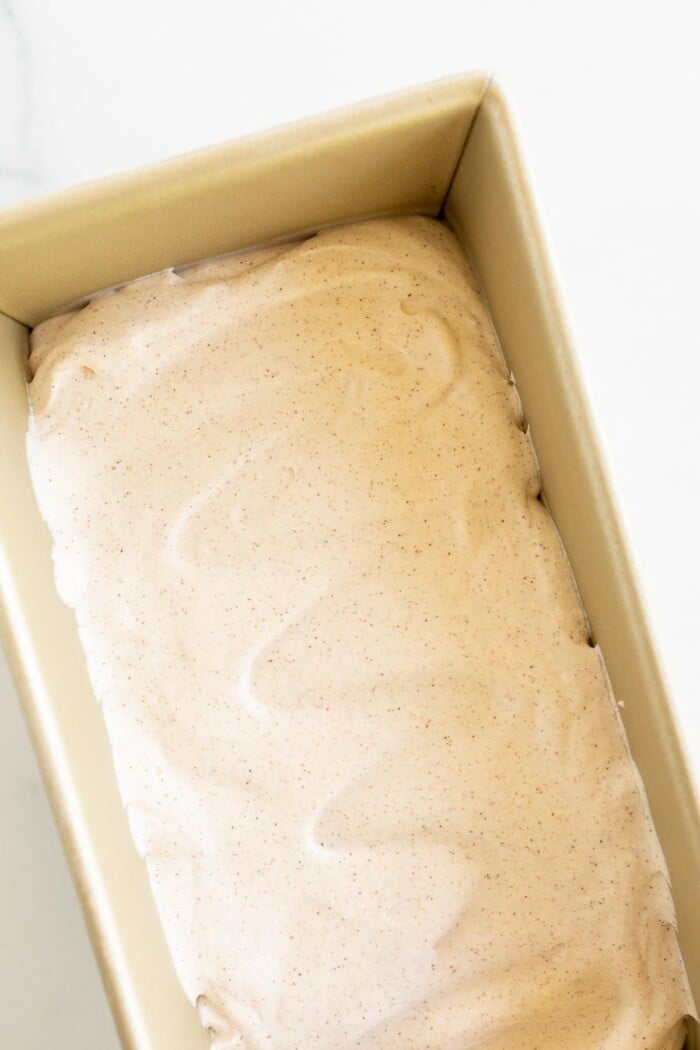 A gold loaf pan full of cinnamon ice cream on a marble surface