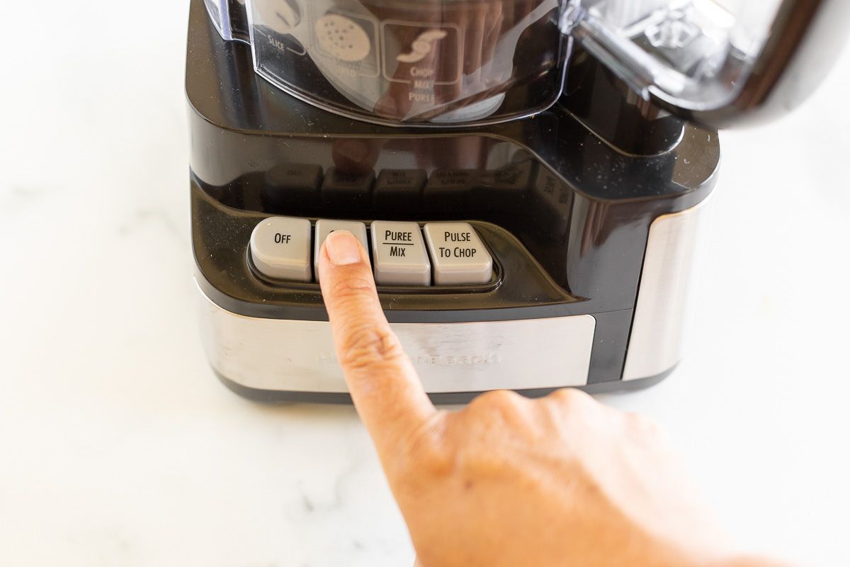 A finger pressing a button on a food processor.