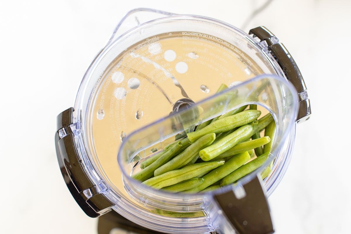 Fresh green beans inside a food processor.