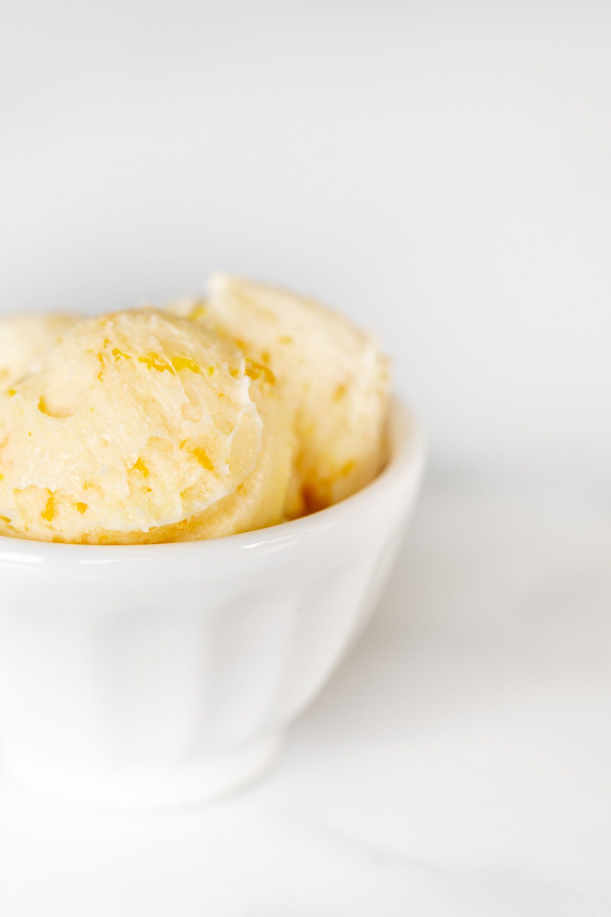 A white bowl filled with butter with specks of orange peel visible throughout.