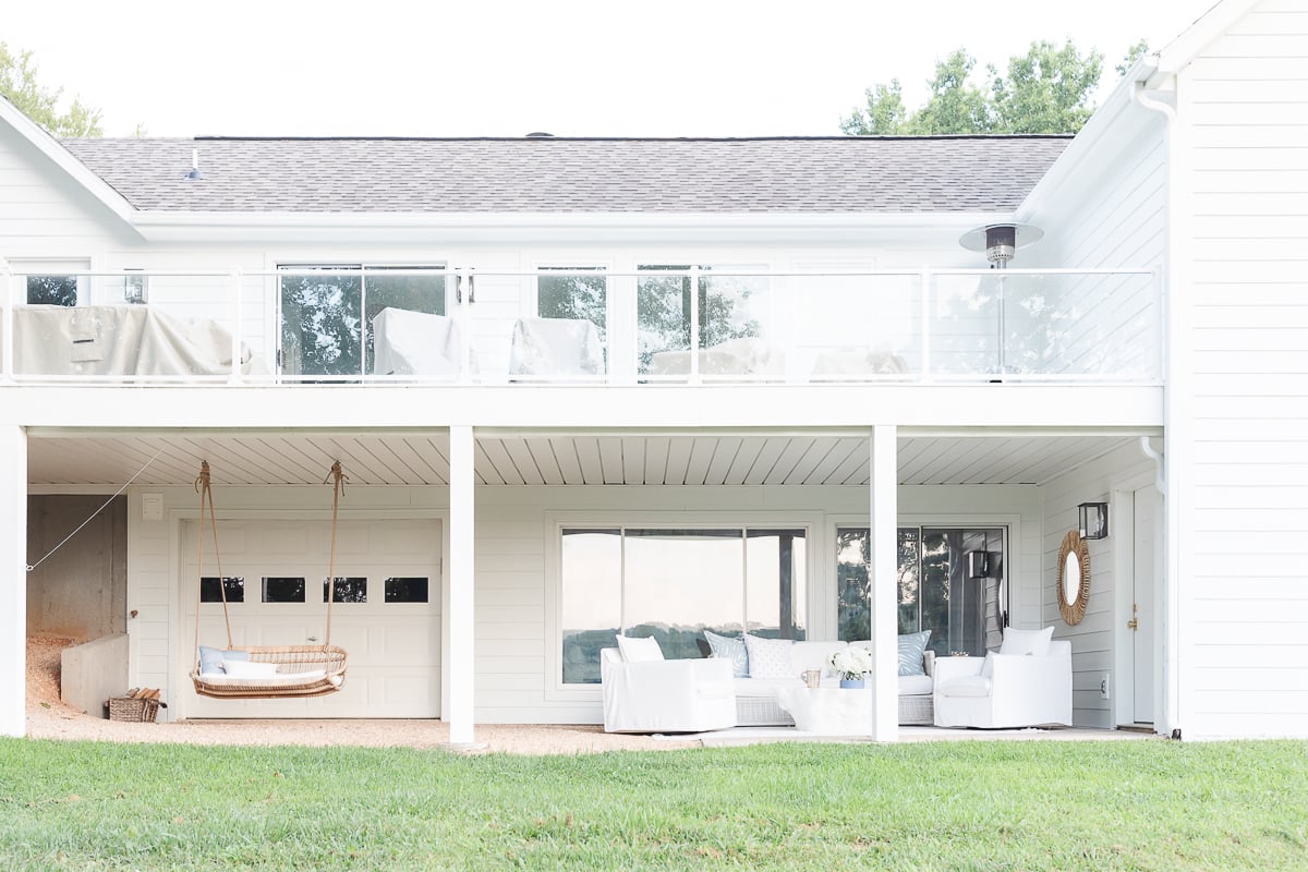 A white house with a wicker swing on the porch.