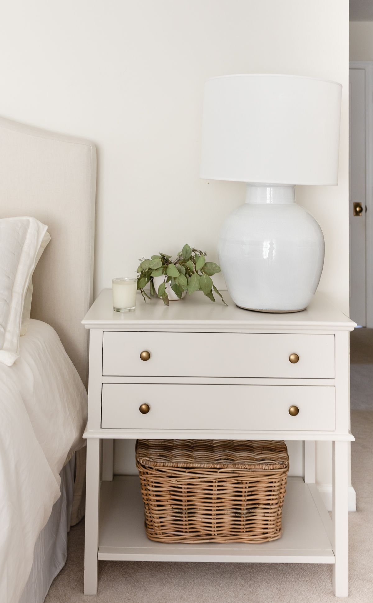 A nightstand in a cream bedroom, painted in Benjamin Moore Pale Oak paint color.