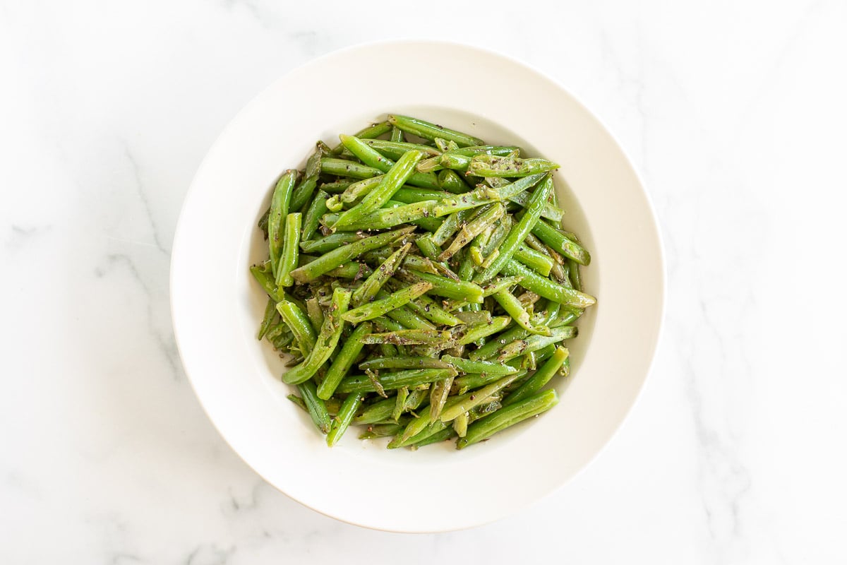 Seasoned green beans on a white plate.