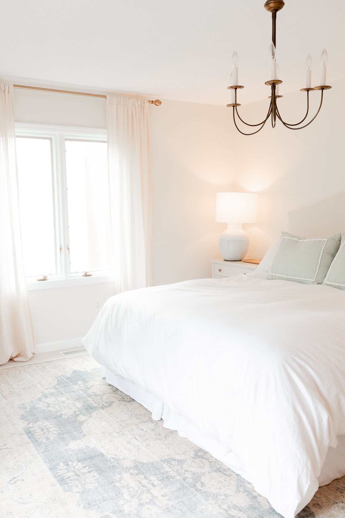 A bedroom with a vintage rug under a king size bed.