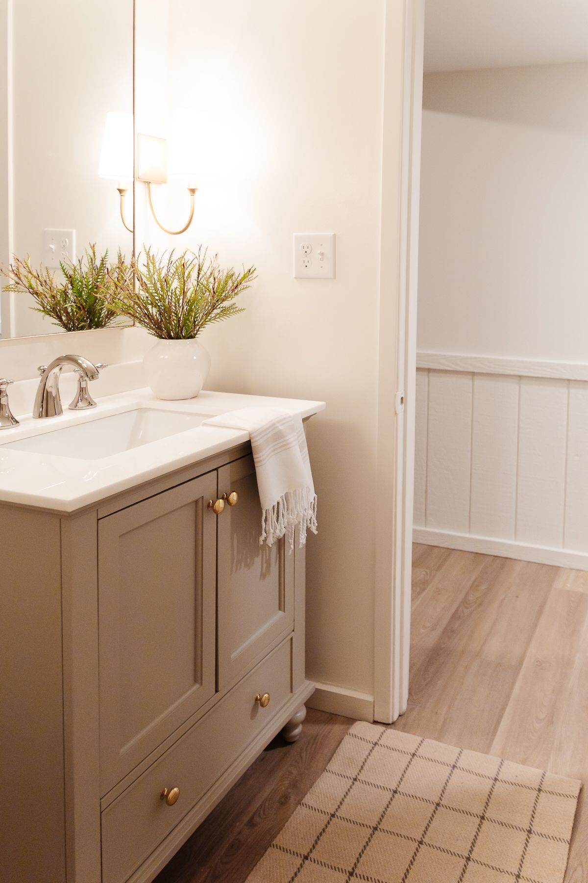 A small bathroom with gold sconces, greige vanity and walls painted Cloud White