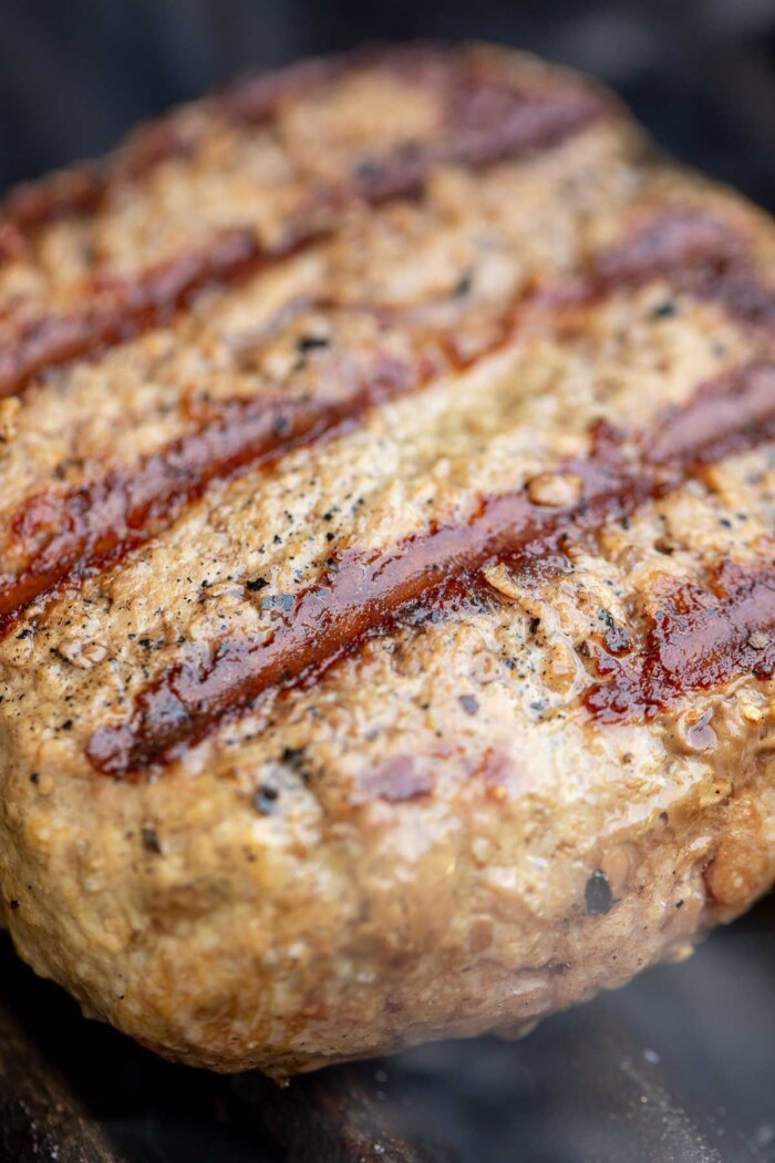 A burger patty recipe with grill lines across the patty, grilling on a grill grate