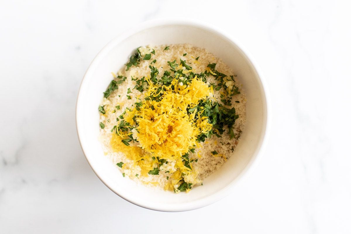 A breading mixture in a bowl, topped with lemon zest and chopped parsley