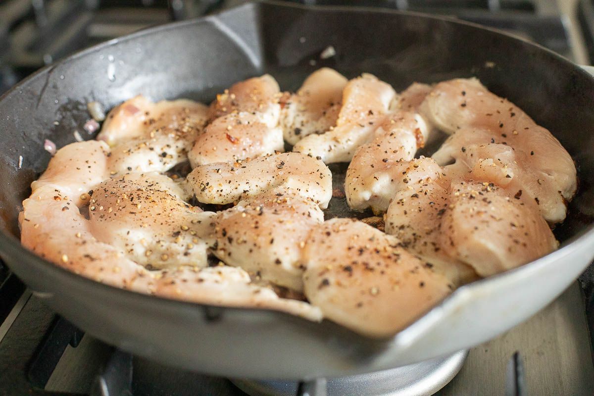 Chicken cutlets cooking in a cast iron skillet