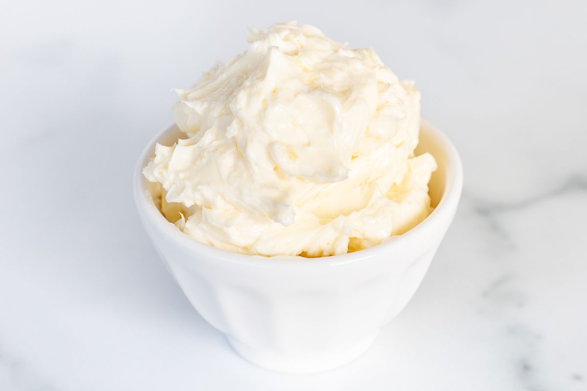 A small white bowl of garlic butter on a marble surface.