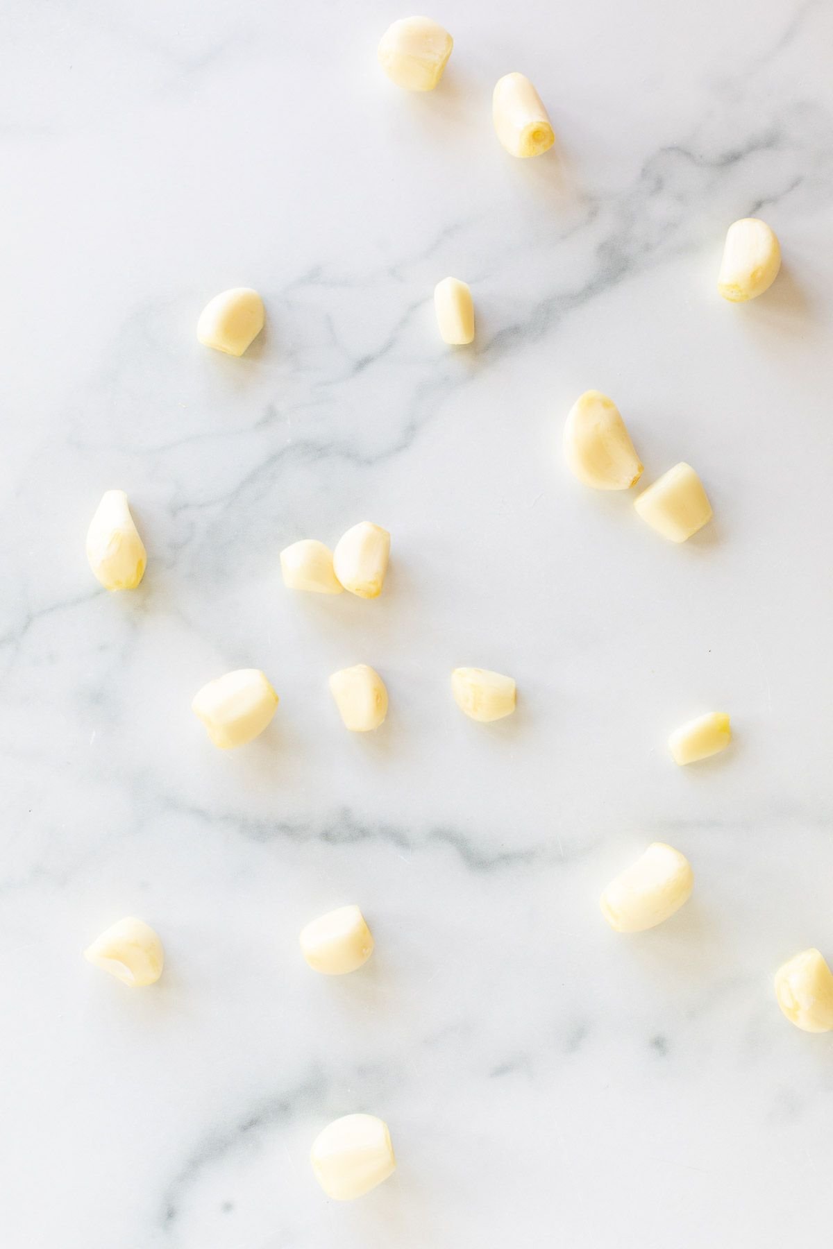 Garlic cloves laid out on a marble surface.