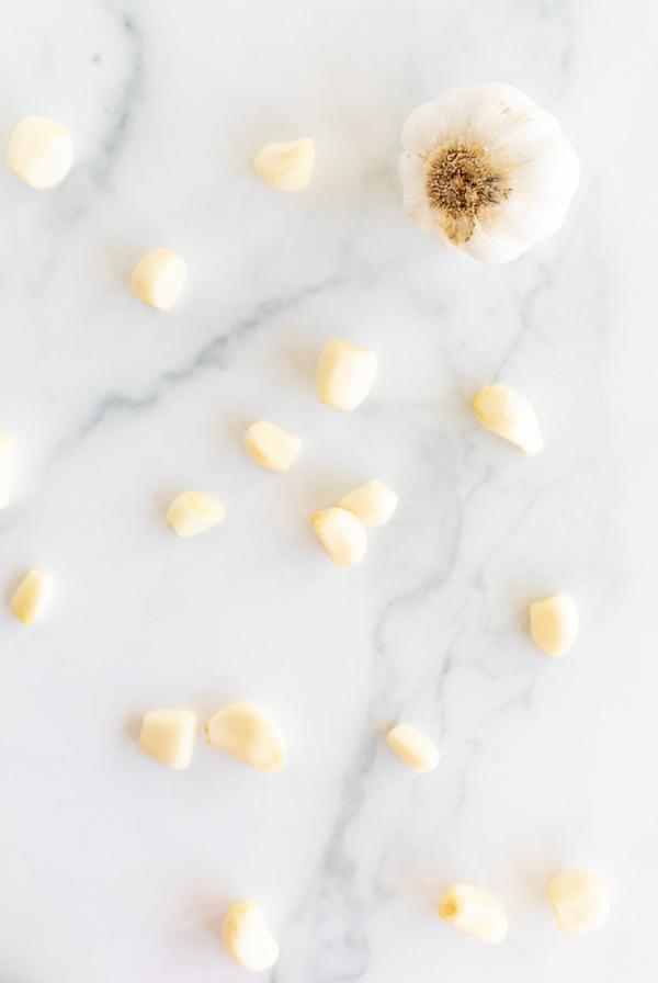 Garlic cloves laid out on a marble surface.