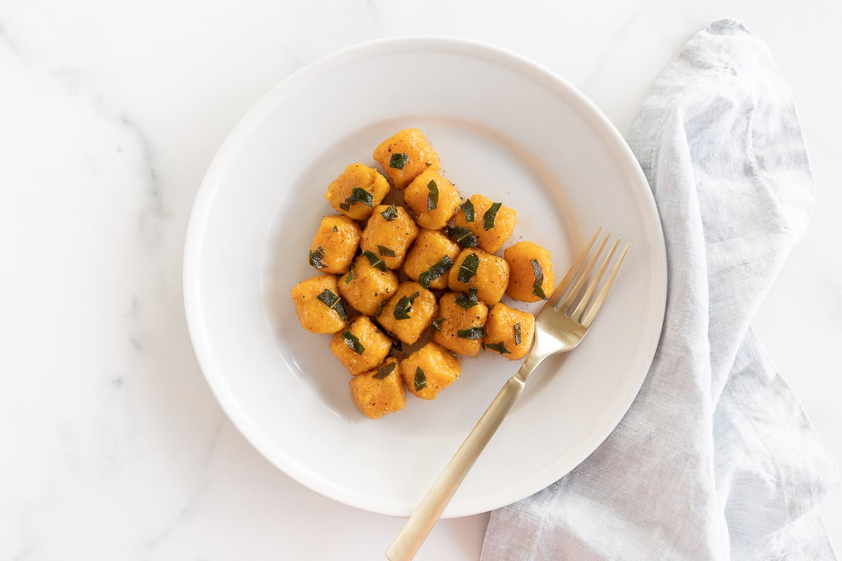 Sweet potato gnocchi on a white plate with a fork.