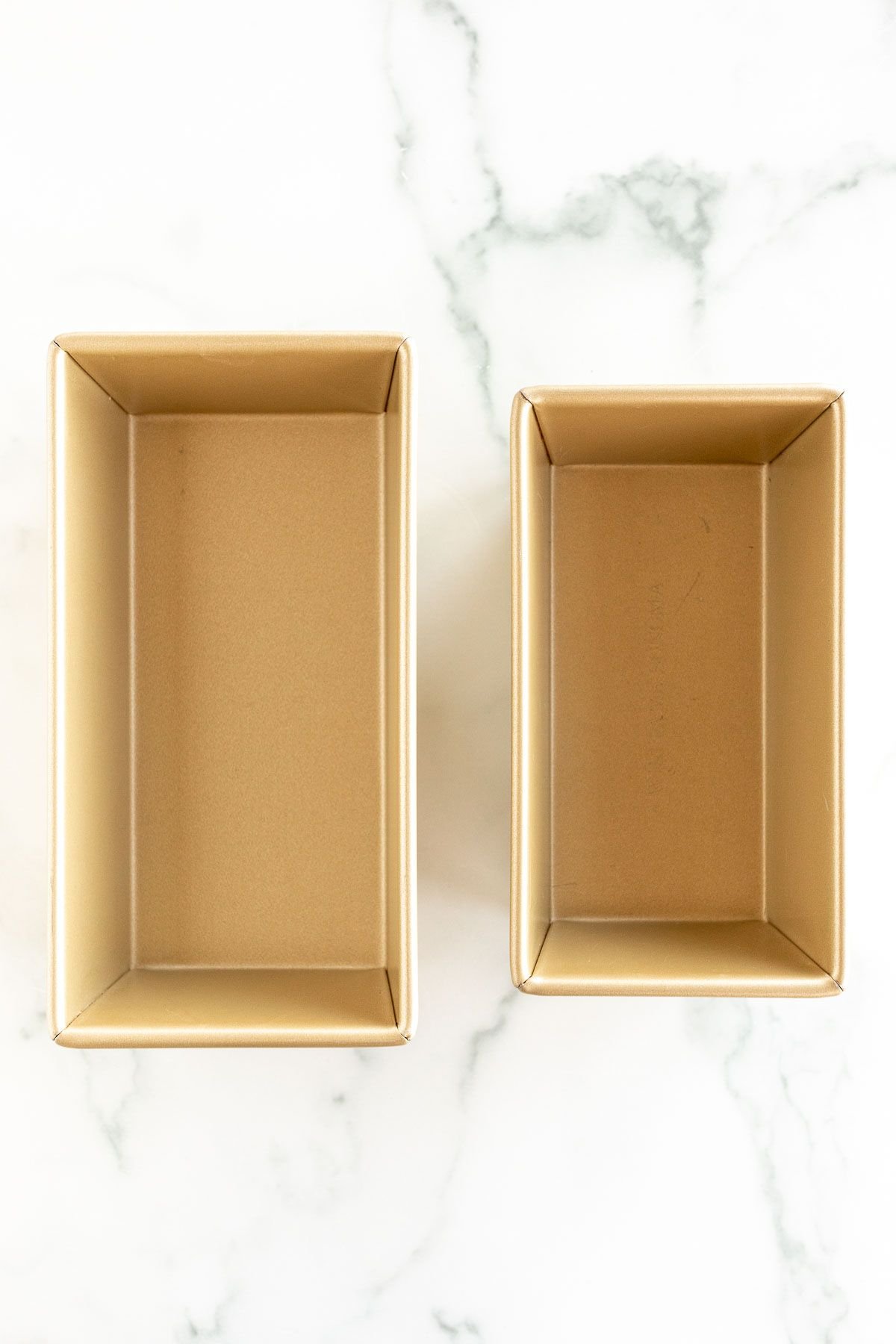 Two loaf baking pan sizes laid out side by side on a marble surface