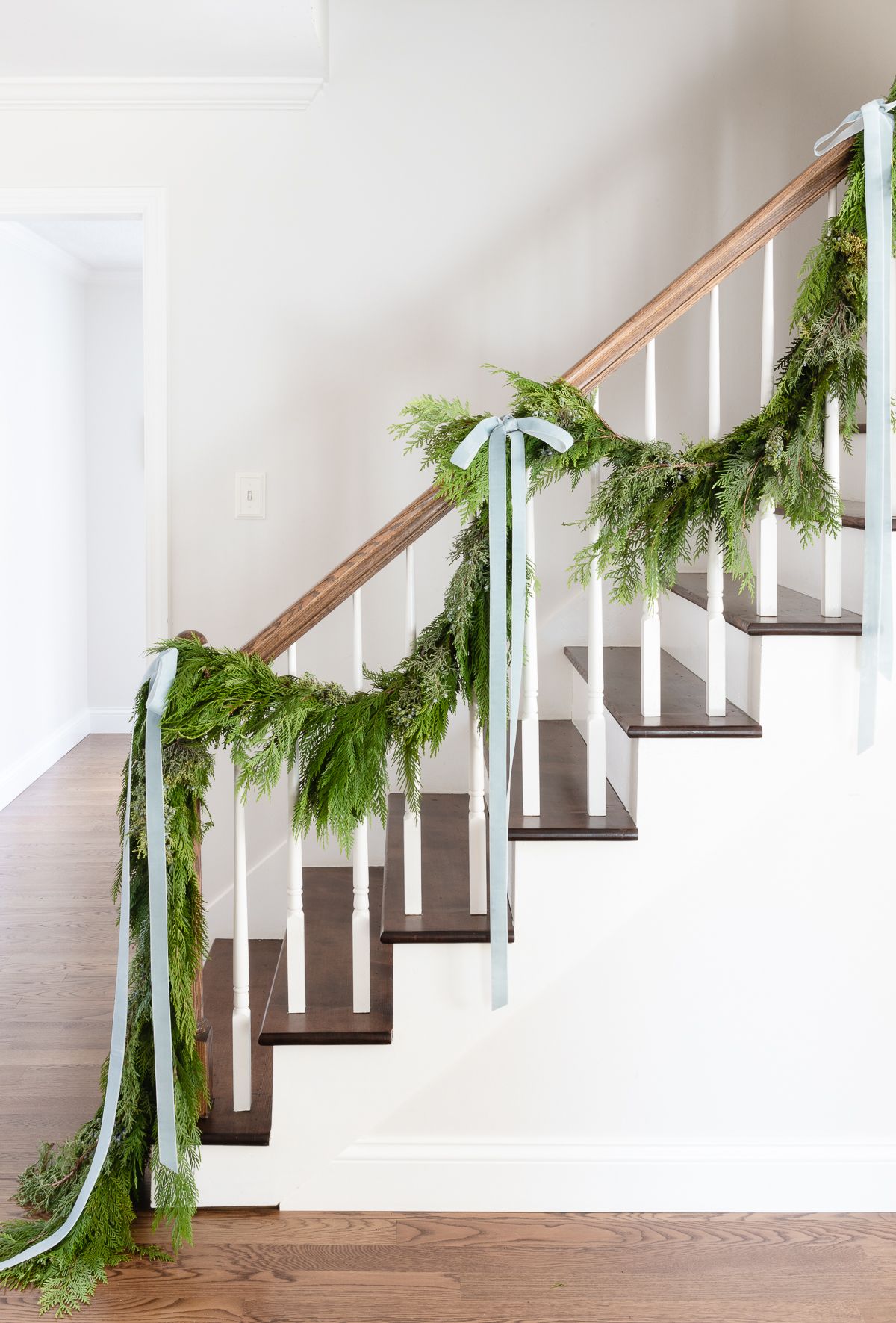 Fresh cedar garland on a staircase, tied with blue ribbon