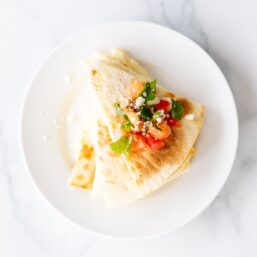 A stack of cheese quesadillas on a white plate