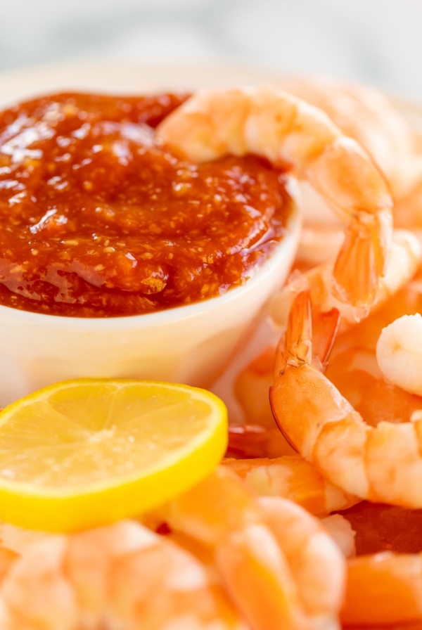 Roasted shrimp cocktail with a homemade cocktail sauce in a white bowl.