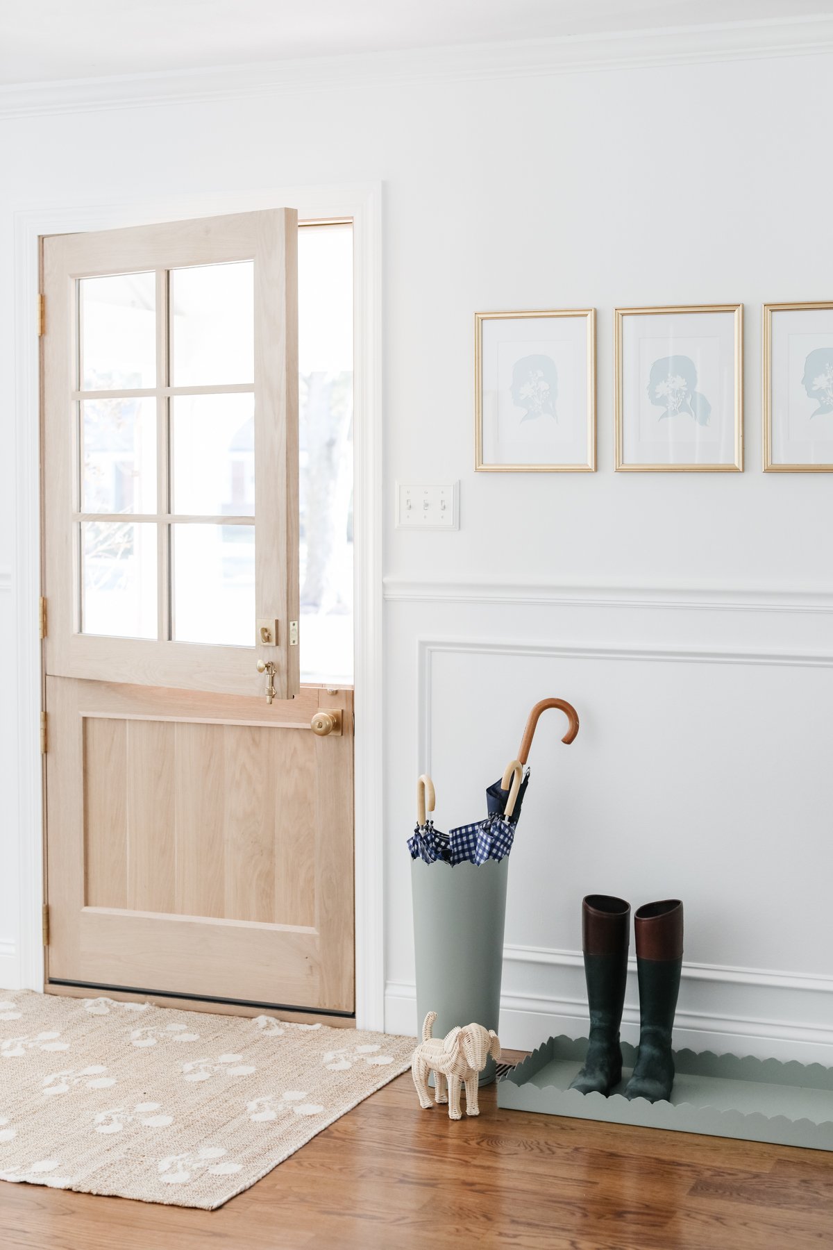 An entryway with a coat rack and a pair of boots, adorned with neutral rugs.