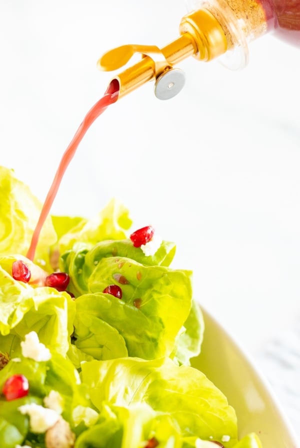 pomegranate vinaigrette pouring out of spout onto salad