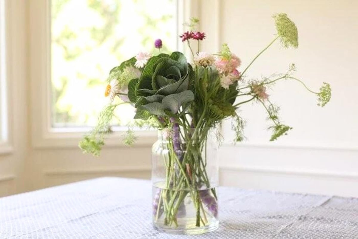 A beautiful Thanksgiving centerpiece, featuring a glass vase filled with flowers, adorns the table.