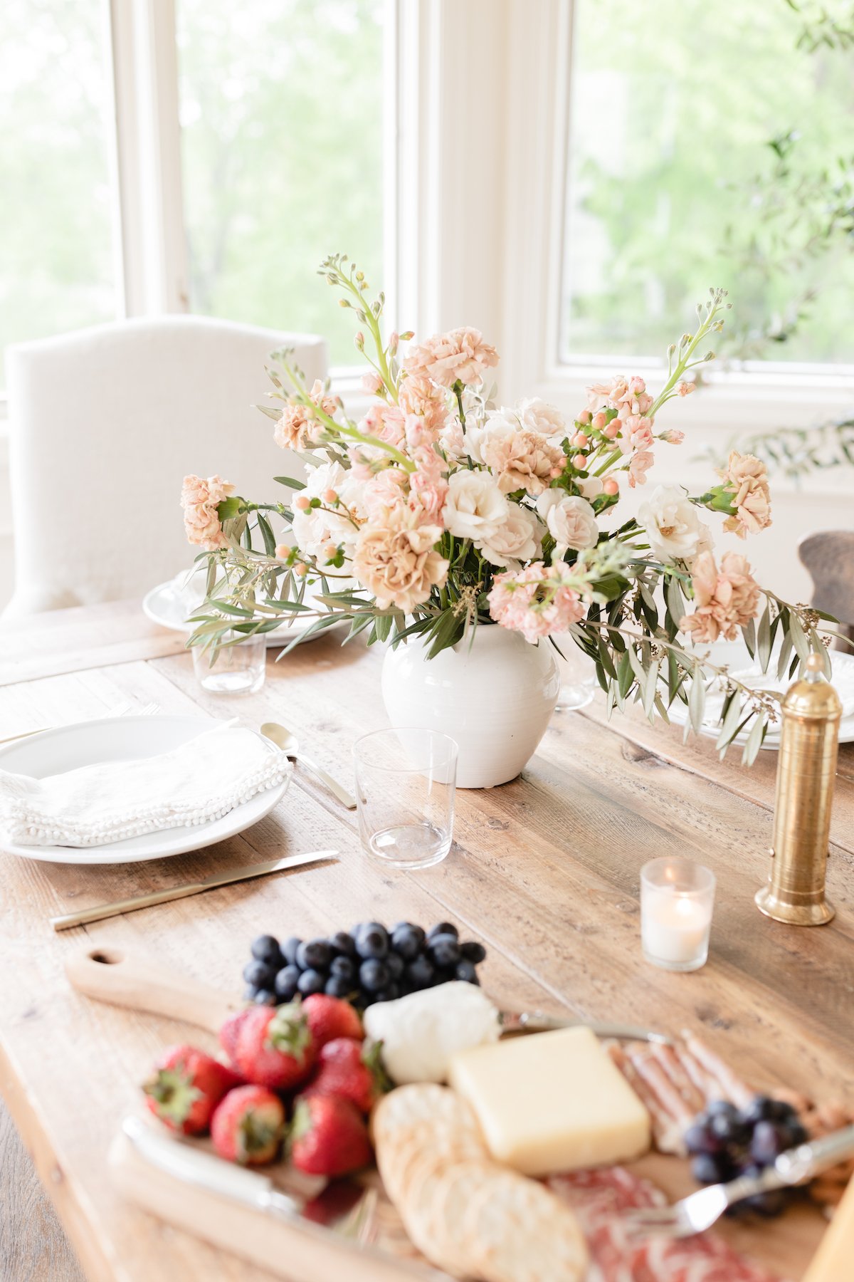 A Thanksgiving table setting adorned with beautiful flowers, delightful fruit arrangements, and delectable cheese platters.