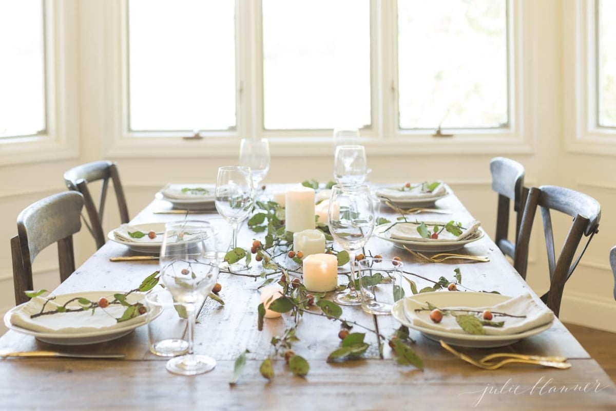 A Thanksgiving table setting adorned with candles and greenery, creating beautiful Thanksgiving centerpieces.