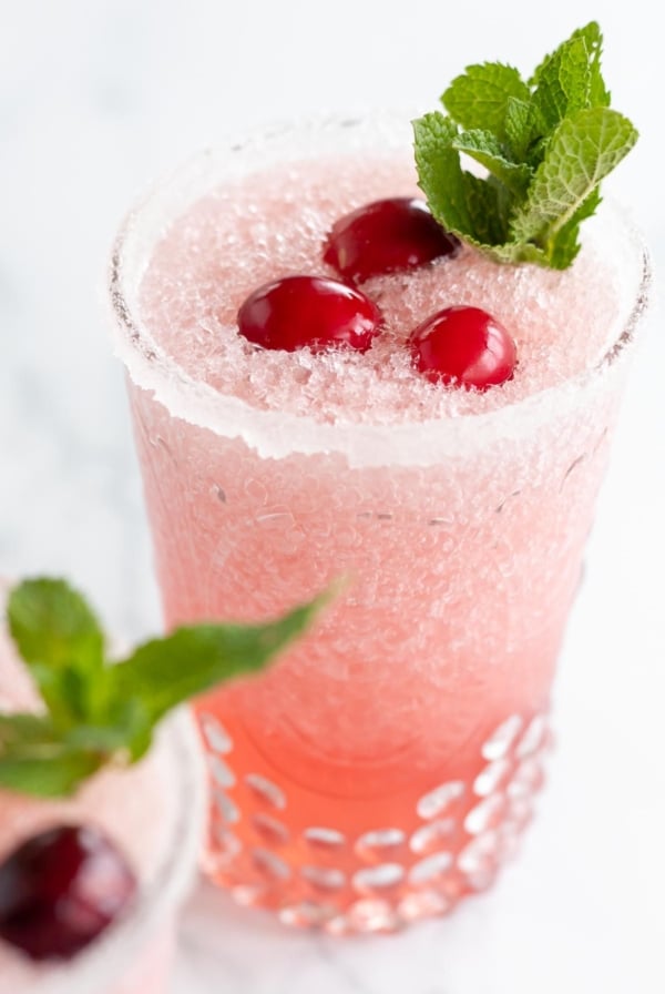 A pair of cranberry margaritas topped with fresh cranberries and mint