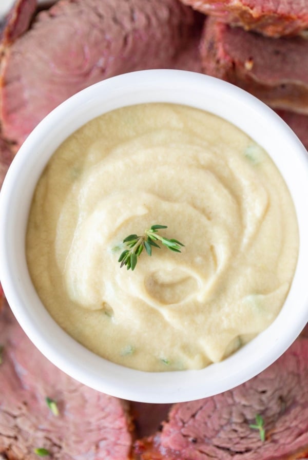 A white bowl full of Dijon sauce, surrounded by beef tenderloin.