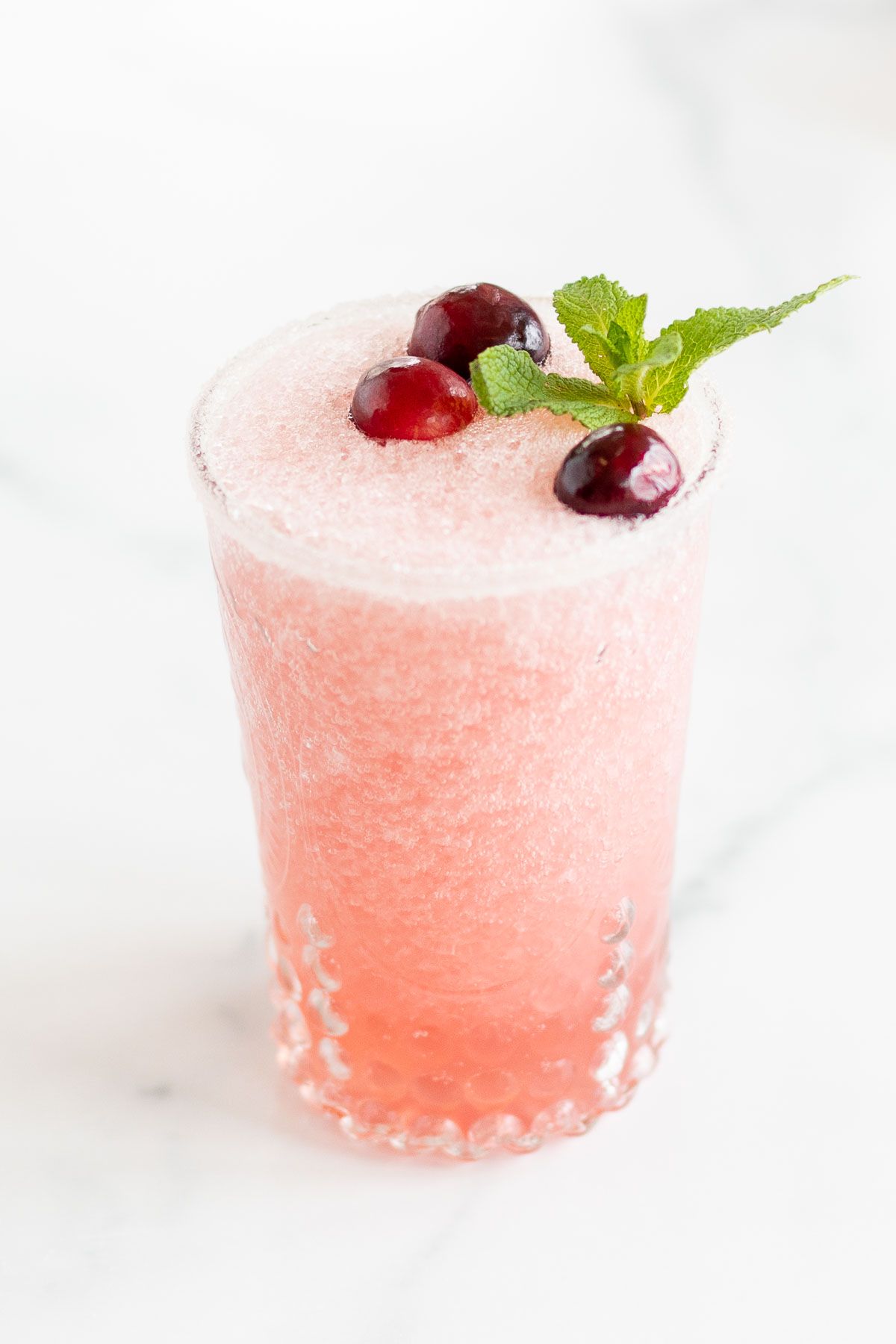 A glass full of a pink toned frozen Mistletoe margarita